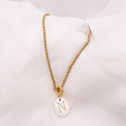 Collier initiale personnalisé en porcelaine artisanale avec lettre au choix. Bijou fait main dans le Sud de la France monté sur une chaîne dorée en acier inoxydable.
