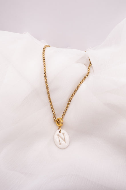 Collier initiale personnalisé en porcelaine artisanale avec lettre au choix. Bijou fait main dans le Sud de la France monté sur une chaîne dorée en acier inoxydable.