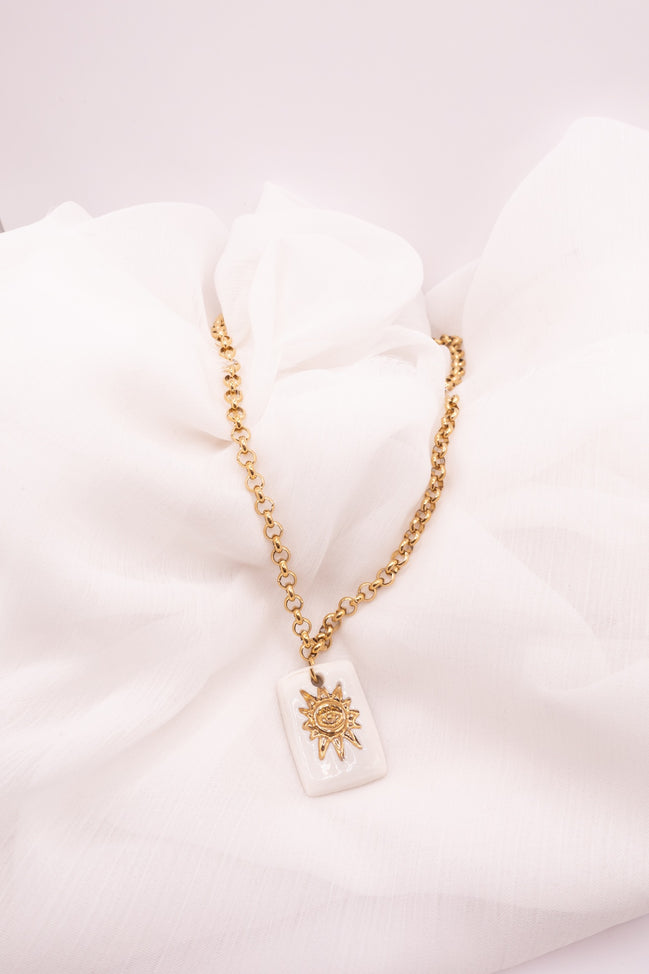 Collier Solis en porcelaine artisanale avec motif soleil doré. Bijou fait main dans le Sud de la France, style bohème chic et symbolique.