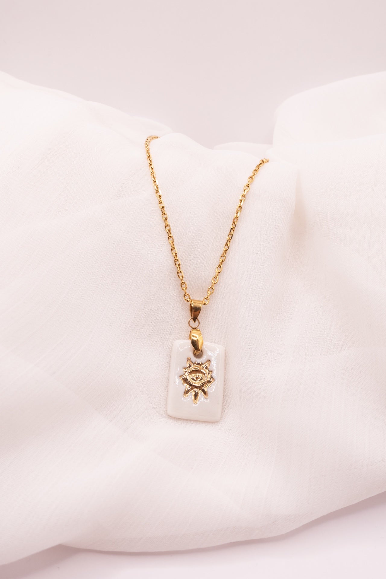 Petit Collier Solis en porcelaine artisanale avec motif soleil doré. Bijou fait main dans le Sud de la France, délicat et lumineux.